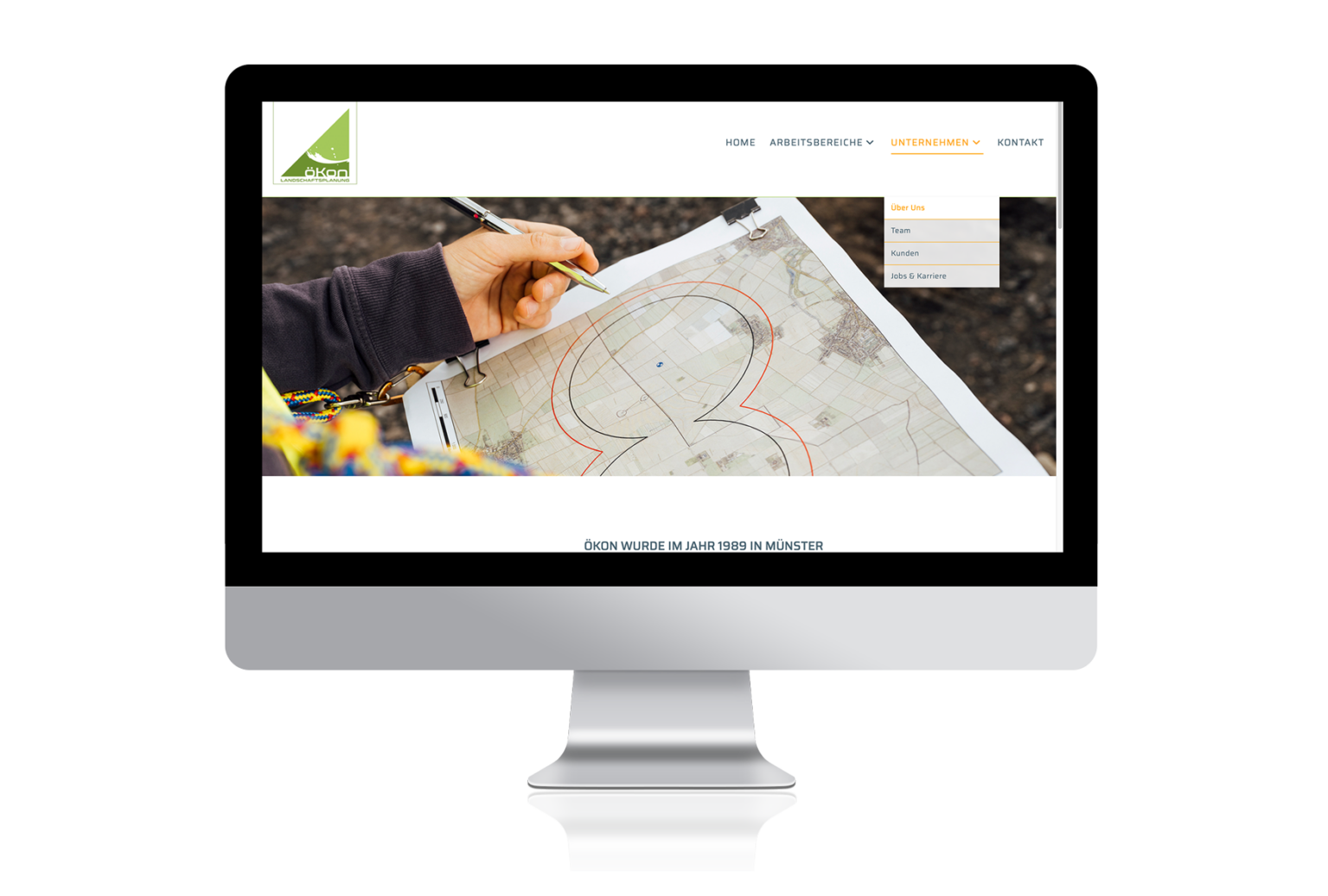 öKon Website: Unternehmen / Über Uns- Mitarbeiterin mit Notizbrett im Gelände trägt Infos auf einem Plan ein.